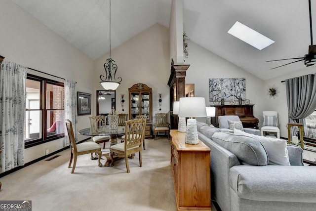 carpeted living room with ceiling fan, high vaulted ceiling, and a skylight