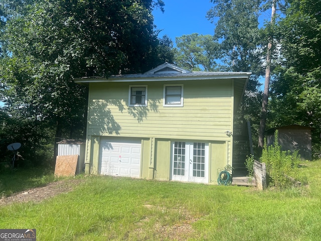 back of property featuring a garage and a lawn