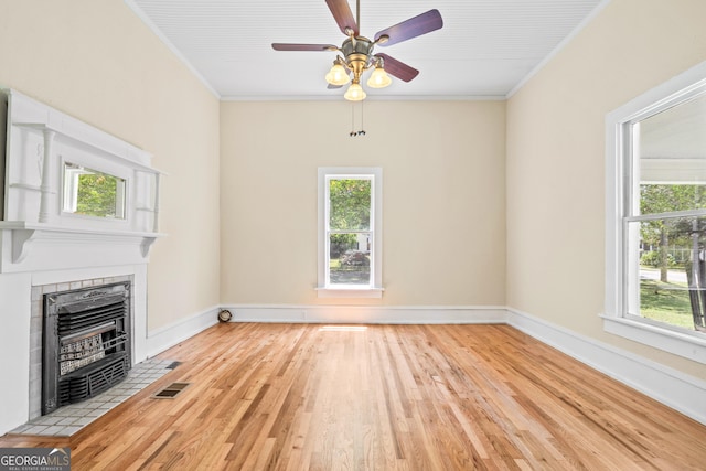 unfurnished living room with light hardwood / wood-style flooring, crown molding, and a wealth of natural light