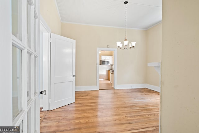 empty room featuring crown molding, a chandelier, and light hardwood / wood-style floors