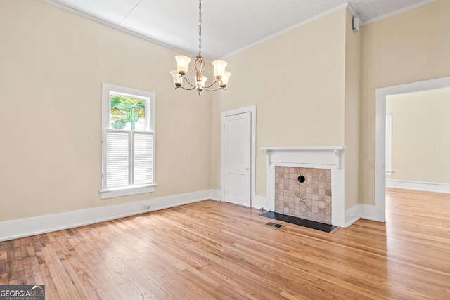 interior space with crown molding, light hardwood / wood-style flooring, a tile fireplace, a notable chandelier, and a high ceiling