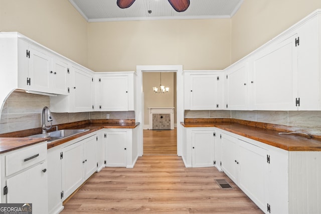 kitchen featuring white cabinetry, sink, ornamental molding, and butcher block counters