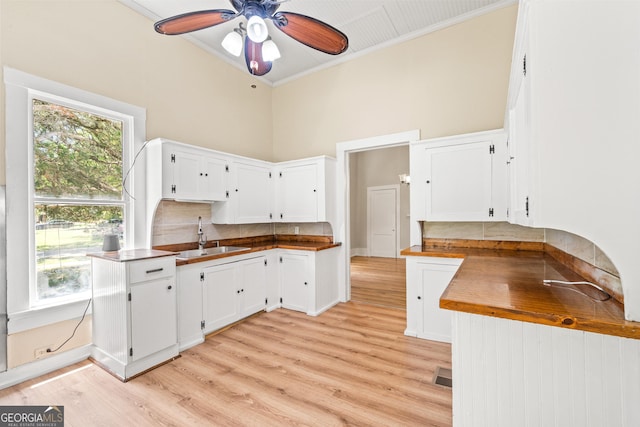 kitchen featuring butcher block counters, sink, backsplash, white cabinets, and ornamental molding