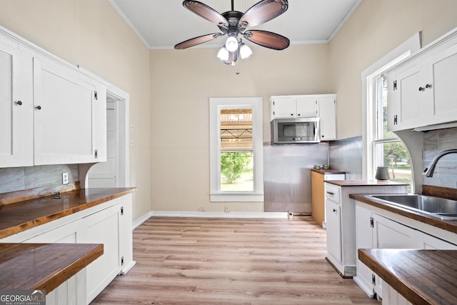 kitchen with white cabinetry, sink, wooden counters, and ornamental molding