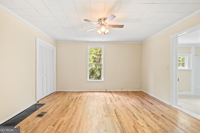 unfurnished bedroom featuring multiple windows, ornamental molding, a closet, and light wood-type flooring