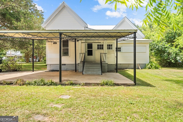 back of property with a carport and a yard