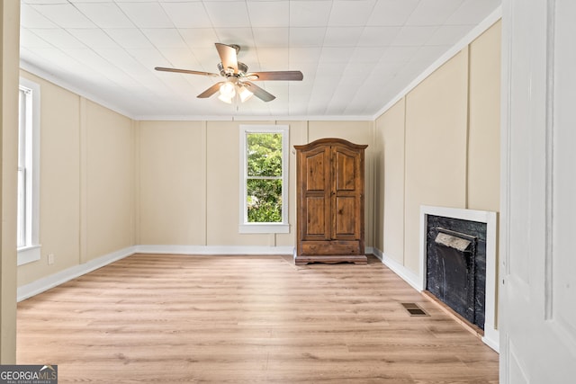 unfurnished living room featuring ornamental molding, ceiling fan, a high end fireplace, and light hardwood / wood-style flooring