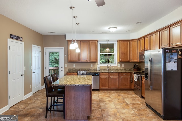 kitchen featuring a healthy amount of sunlight, stainless steel appliances, a kitchen bar, and pendant lighting