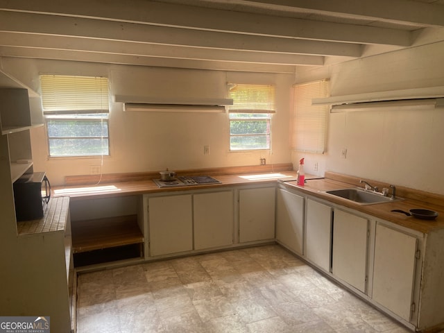 kitchen with stainless steel gas stovetop, sink, and beamed ceiling