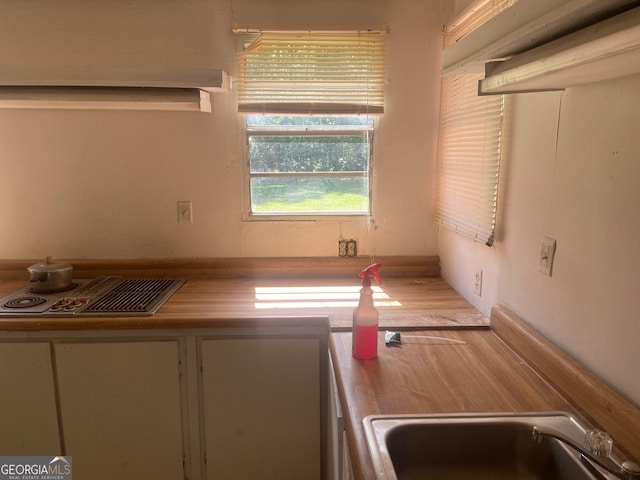 kitchen with wooden counters, cooktop, and sink