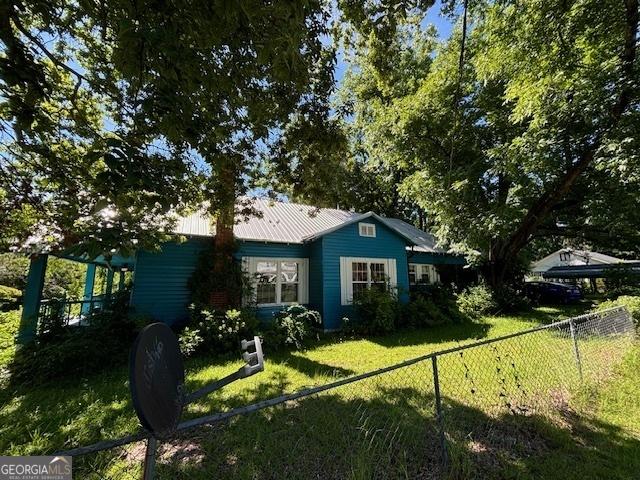 exterior space featuring fence, metal roof, and a yard