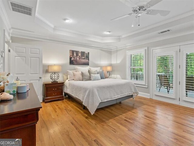 bedroom featuring ceiling fan, light wood-type flooring, a raised ceiling, access to outside, and ornamental molding