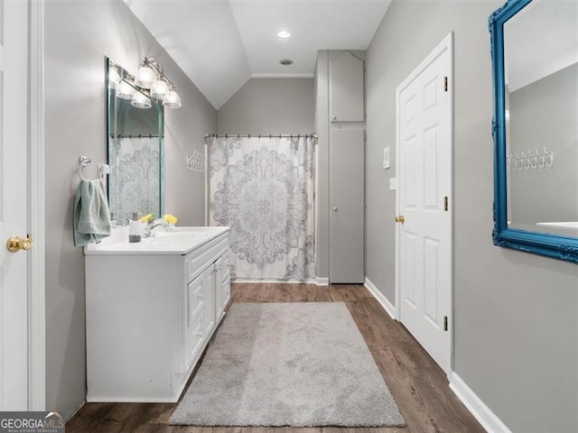 bathroom with vaulted ceiling, hardwood / wood-style floors, and vanity