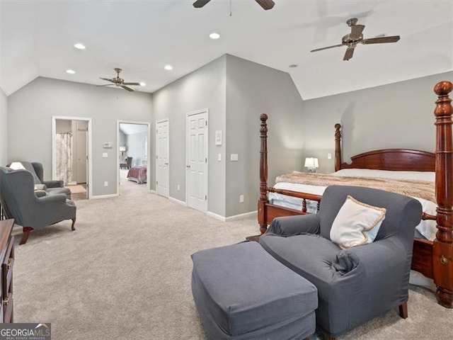 bedroom with ceiling fan, vaulted ceiling, ensuite bath, and light carpet