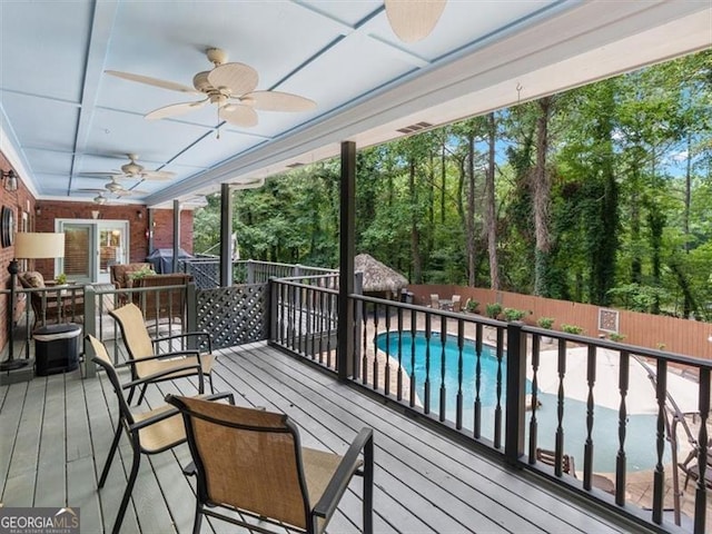 wooden deck with ceiling fan and a fenced in pool