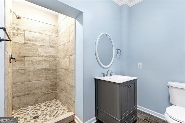 bathroom featuring toilet, crown molding, vanity, and tiled shower