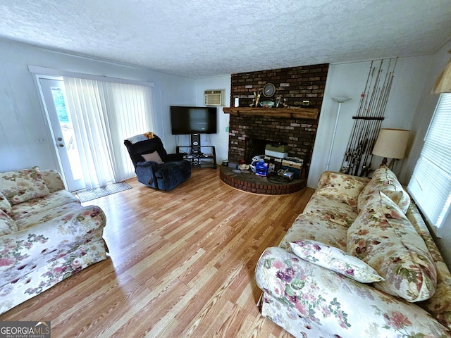 living room featuring light hardwood / wood-style floors, a brick fireplace, brick wall, and a textured ceiling