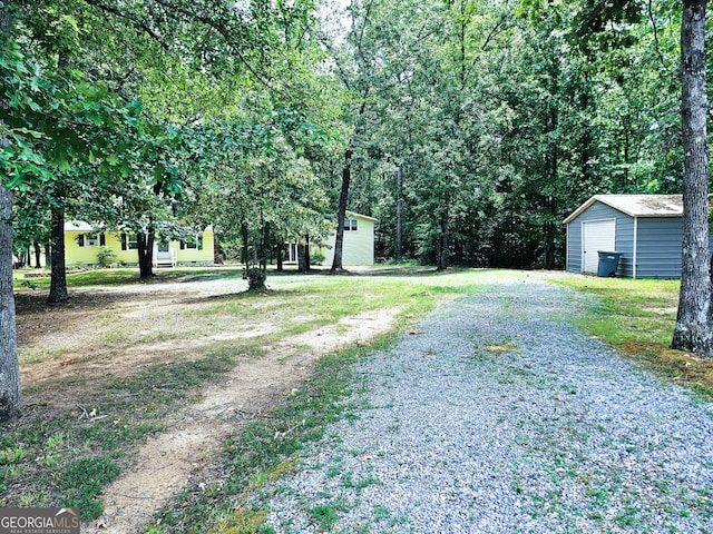 view of yard featuring a detached garage, an outdoor structure, and driveway