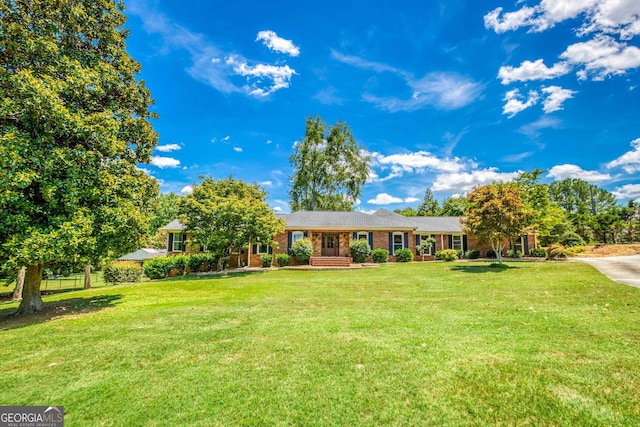 ranch-style home with brick siding, fence, and a front lawn
