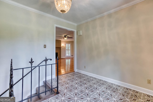 spare room with crown molding, baseboards, a fireplace, and ceiling fan with notable chandelier
