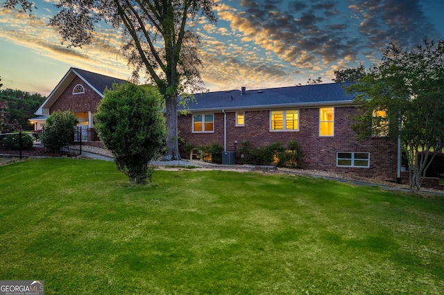 view of front of home with central AC, a front lawn, and brick siding