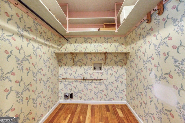 clothes washing area featuring laundry area, wood finished floors, baseboards, hookup for a washing machine, and wallpapered walls