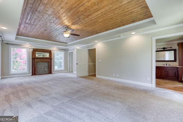unfurnished living room featuring light carpet, baseboards, a tray ceiling, ornamental molding, and wood ceiling
