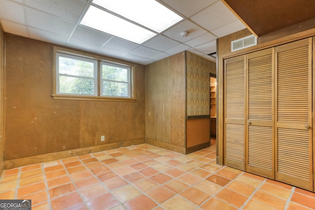 basement with baseboards, tile patterned floors, a paneled ceiling, and visible vents
