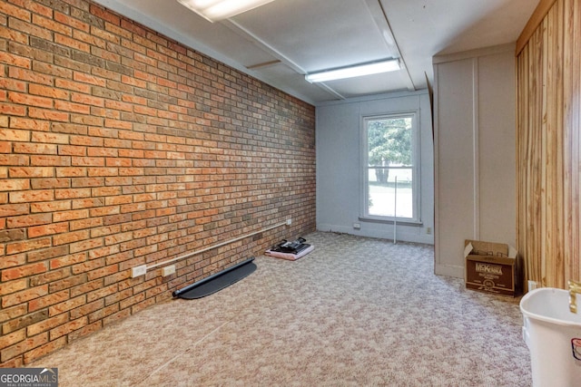 carpeted spare room with brick wall