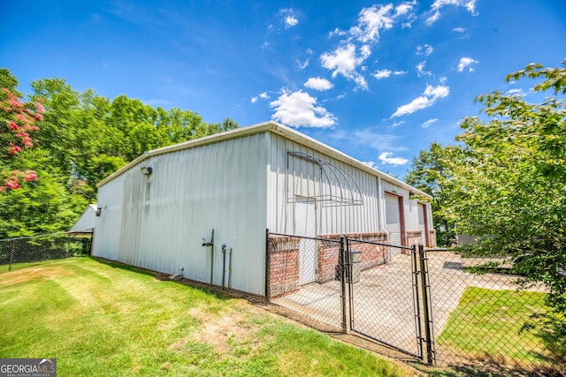 view of side of property featuring a garage, fence, a gate, a lawn, and an outbuilding