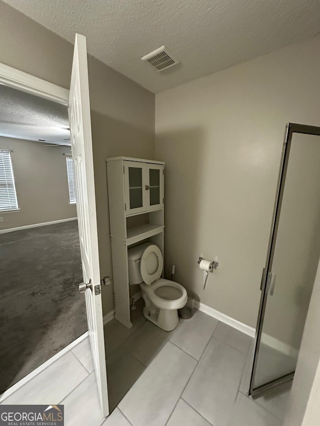 bathroom with tile patterned flooring, toilet, and a textured ceiling