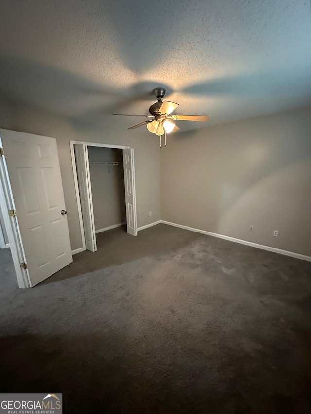 unfurnished bedroom with ceiling fan, a textured ceiling, and dark colored carpet