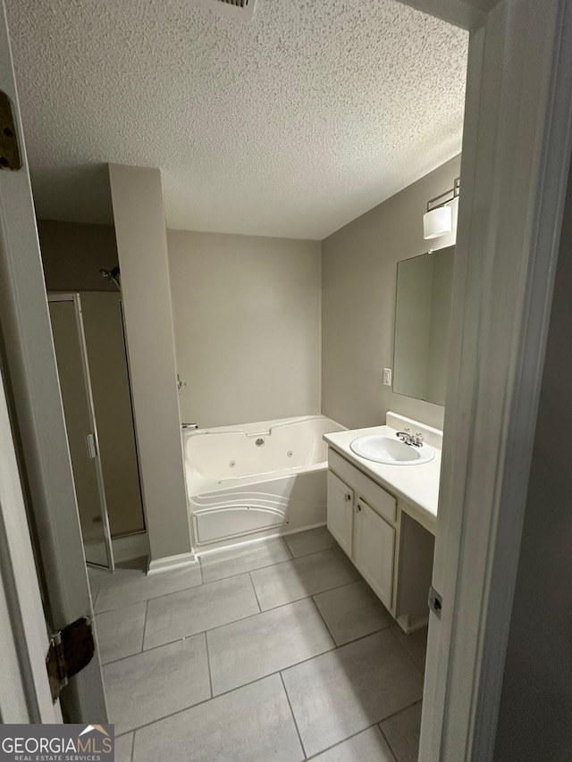 bathroom featuring tile patterned flooring, vanity, separate shower and tub, and a textured ceiling