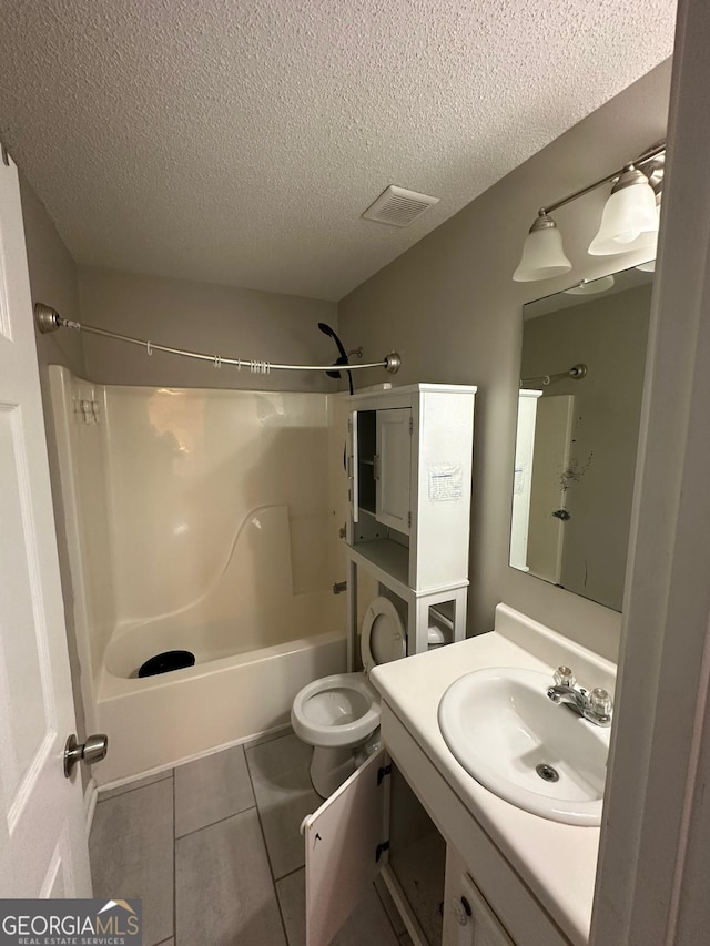 full bathroom featuring vanity, bathtub / shower combination, tile patterned floors, toilet, and a textured ceiling