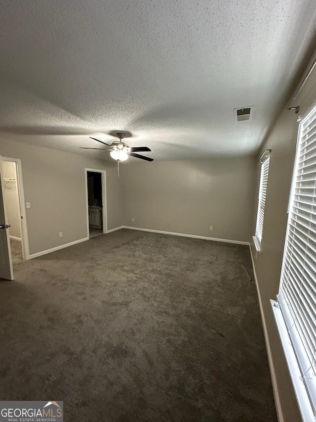 carpeted empty room with ceiling fan and a textured ceiling