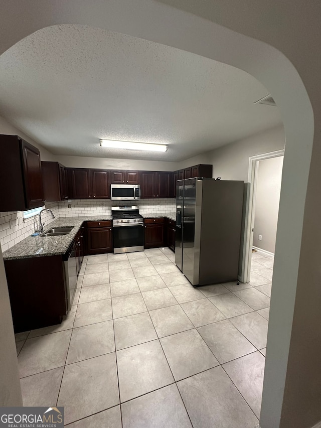 kitchen featuring a textured ceiling, decorative backsplash, sink, and stainless steel appliances