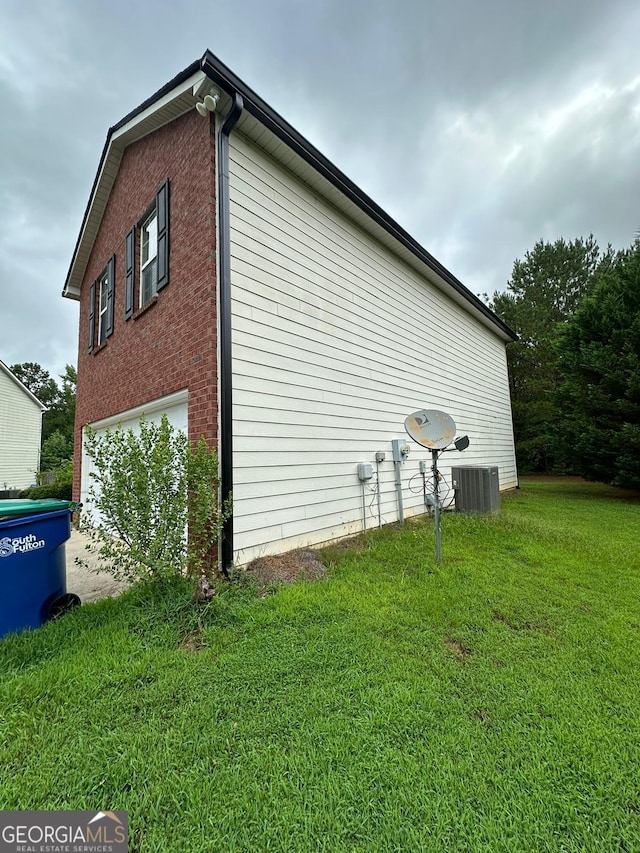 view of side of property featuring a yard, central AC unit, and a garage