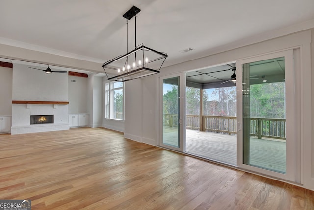 unfurnished living room with ceiling fan, ornamental molding, a fireplace, and light hardwood / wood-style flooring