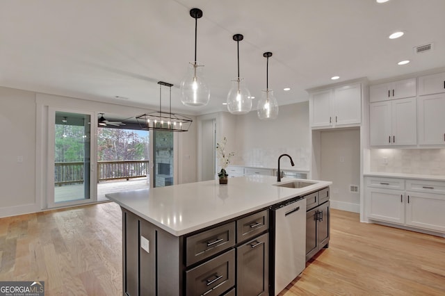 kitchen featuring sink, white cabinetry, decorative light fixtures, stainless steel dishwasher, and a kitchen island with sink