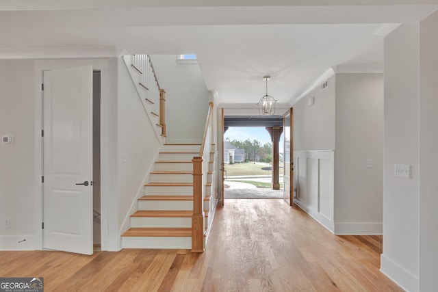 entryway featuring ornamental molding, a chandelier, and light hardwood / wood-style floors