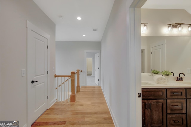 corridor featuring sink and light wood-type flooring