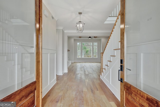 interior space featuring crown molding, light hardwood / wood-style flooring, and a notable chandelier