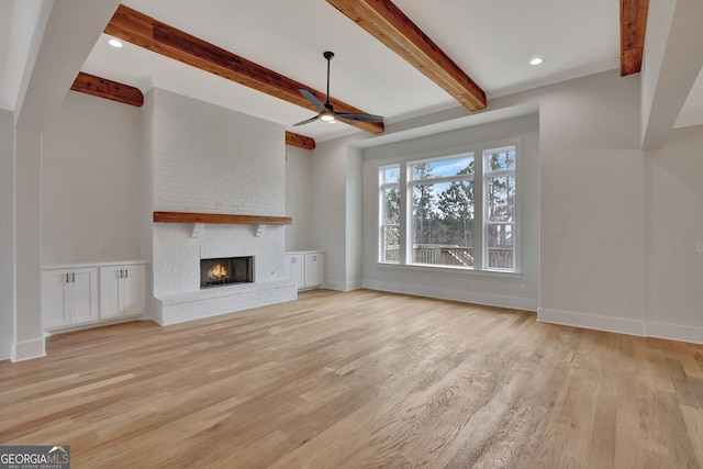 unfurnished living room with a brick fireplace, beam ceiling, light hardwood / wood-style floors, and ceiling fan