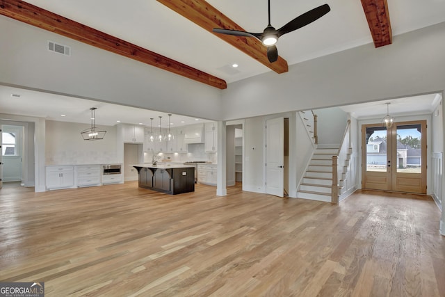 unfurnished living room featuring ceiling fan, sink, beam ceiling, and light hardwood / wood-style flooring