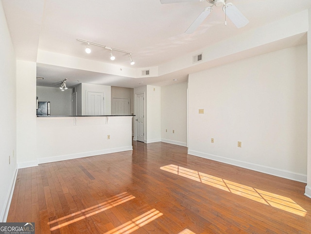 unfurnished living room with wood-type flooring, visible vents, and baseboards