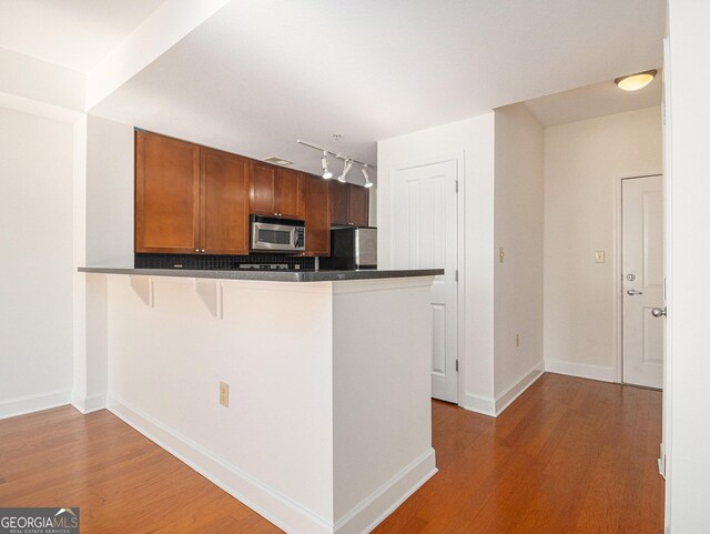 kitchen with dark countertops, wood finished floors, stainless steel microwave, and fridge