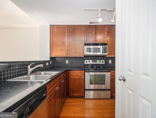 kitchen featuring light wood-style flooring, a sink, visible vents, appliances with stainless steel finishes, and dark countertops