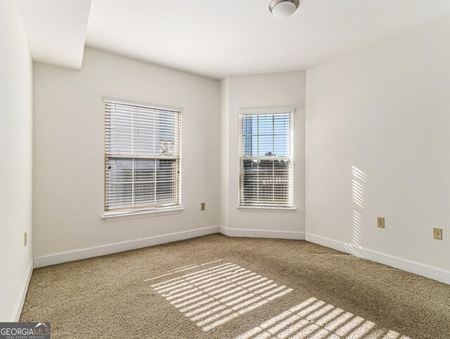 carpeted spare room featuring baseboards
