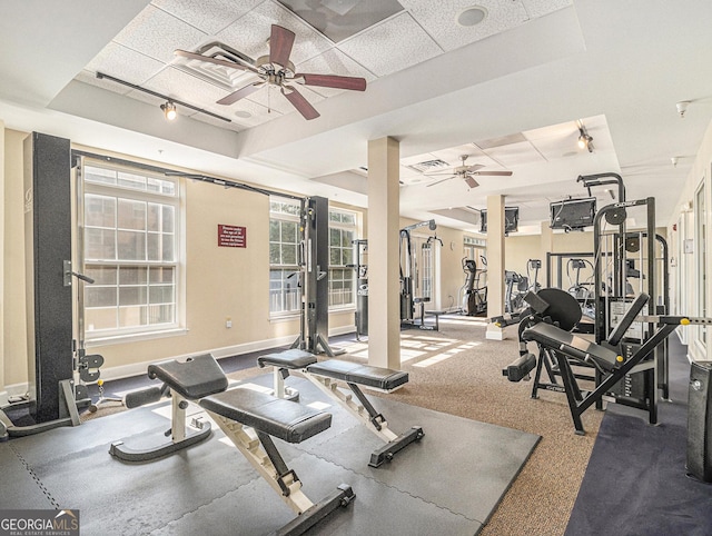 gym with a raised ceiling, ceiling fan, and baseboards