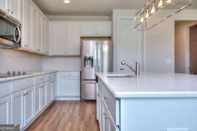 kitchen featuring a kitchen island with sink, white cabinetry, stainless steel appliances, and hardwood / wood-style flooring